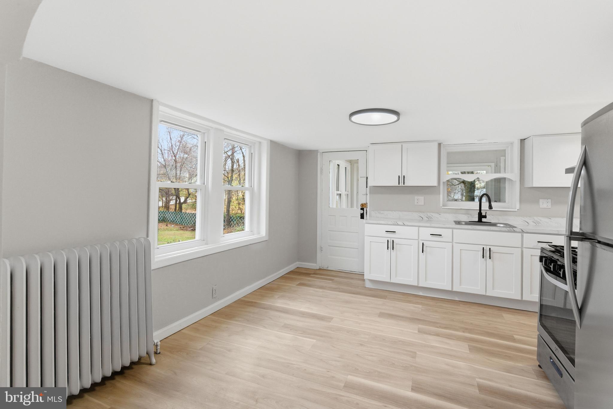 409 Cedar Avenue Lindenwold, NJ 08021 - Photo 9 of 25 a kitchen with stainless steel appliances granite countertop a stove a sink and white cabinets with wooden floor