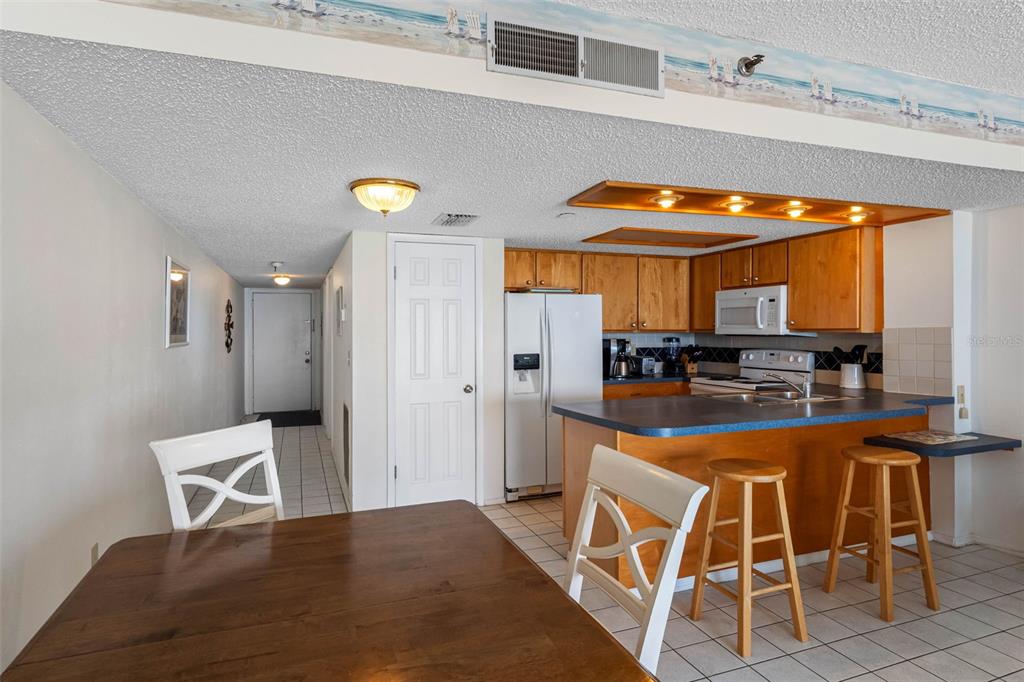 19440 Gulf Boulevard, Unit 506 Indian Rocks Beach, FL 33785 - Photo 63 of 67 a kitchen with stainless steel appliances a dining table chairs and a refrigerator