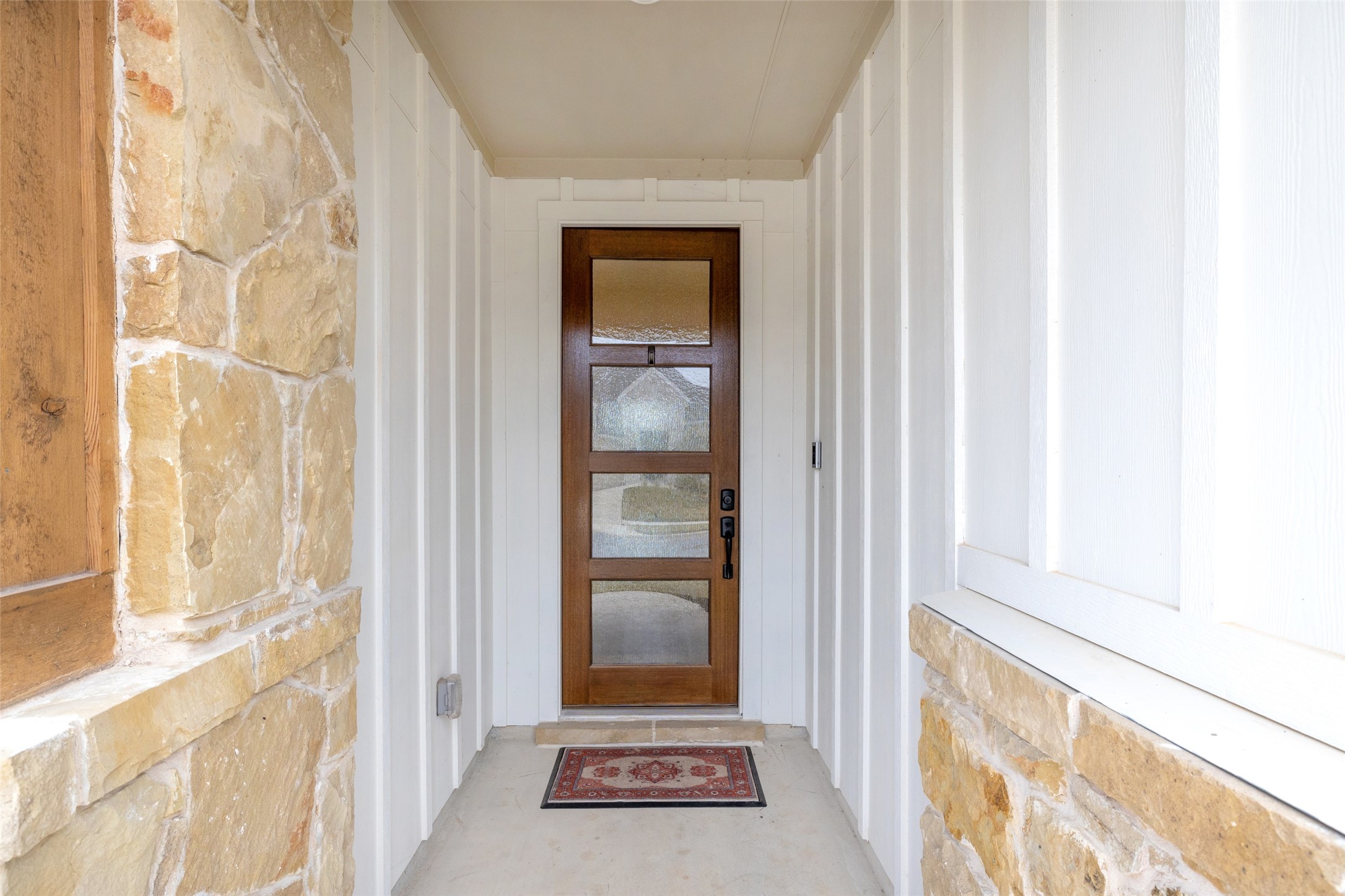 1117 Spring Gulch Lane Georgetown, TX 78628 - Photo 9 of 39 A welcoming entry features a stylish wood door with glass inserts framed by modern white board-and-batten siding.