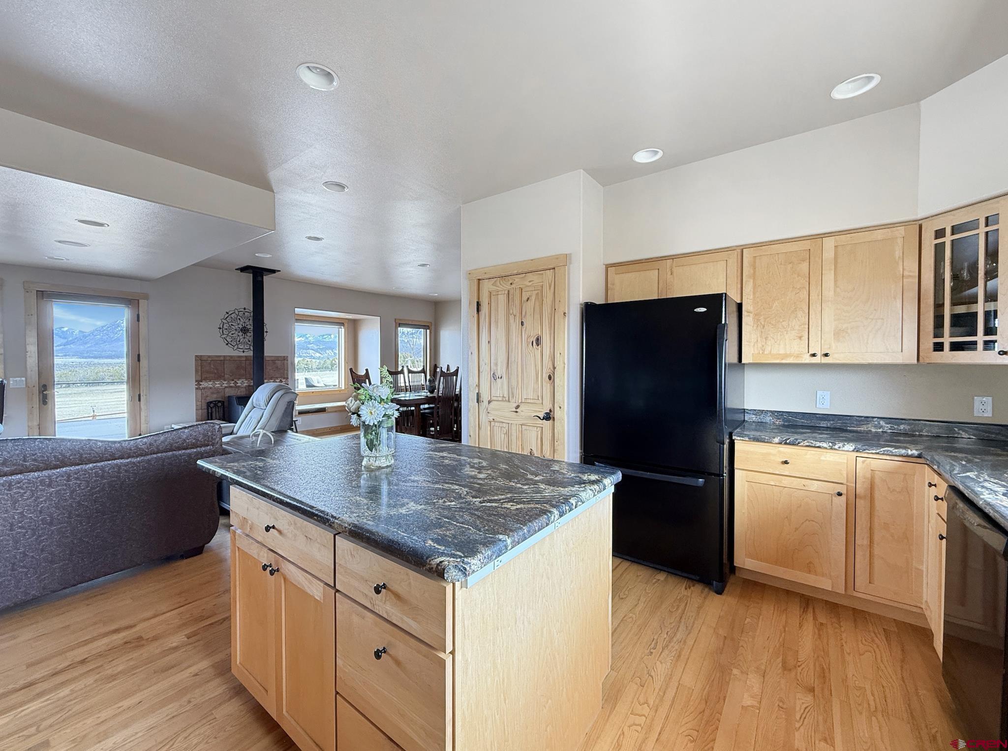 1190 7745 Road Crawford, CO 81415 - Photo 13 of 43 a kitchen with granite countertop a refrigerator a sink dishwasher and wooden cabinets with wooden floor