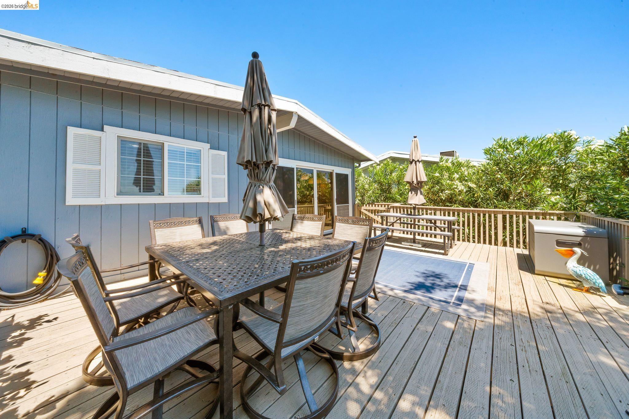 1704 Taylor Road Bethel Island, CA 94511 - Photo 50 of 73 Spacious outdoor deck featuring wood flooring, a surrounding wood railing, and a blue exterior wall with white window shutters