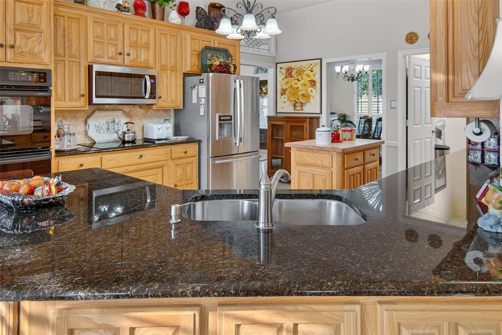 272 Edward Farris Road Weatherford, TX 76085 - Photo 14 of 40 Kitchen featuring granite countertops, a stainless steel sink with a gooseneck faucet, light wood cabinetry, and stainless steel appliances
