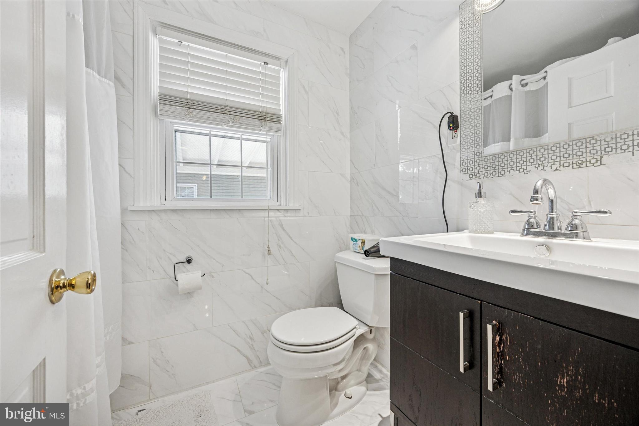 306 East Springfield Road Springfield, PA 19064 - Photo 26 of 40 a bathroom with a toilet a sink a mirror a window and vanity