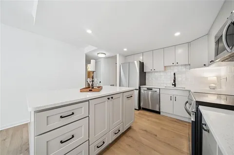 a kitchen with white cabinets sink and stove