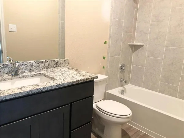 a bathroom with a granite countertop sink and a bathtub