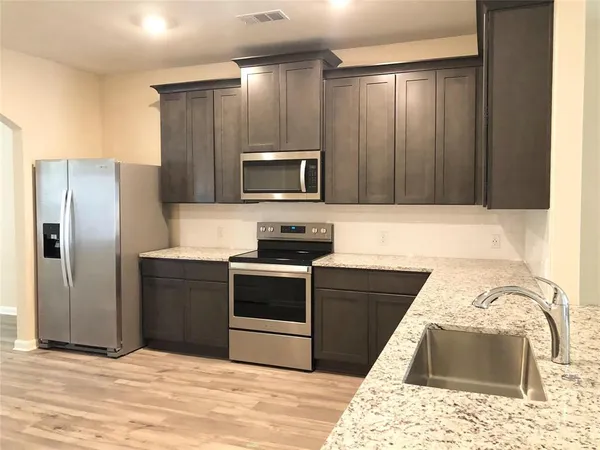 a kitchen with granite countertop a refrigerator and a stove top oven