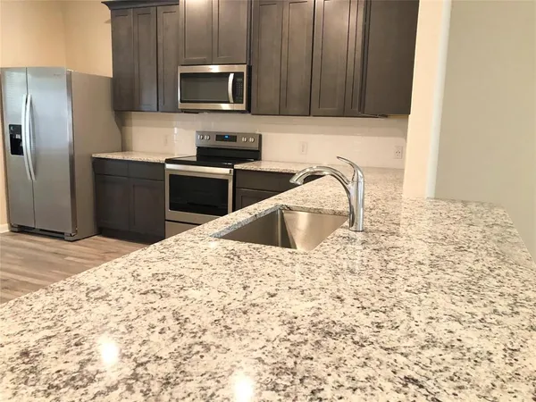 a kitchen with kitchen island granite countertop a sink stainless steel appliances and granite counter tops