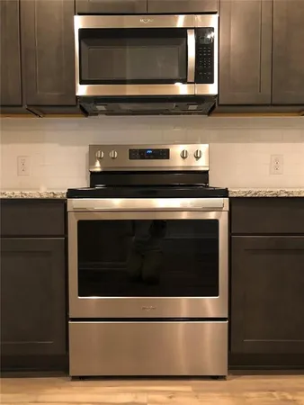 a kitchen with granite countertop a stove and a microwave