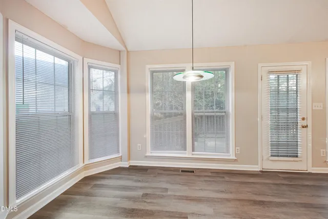 a view of an empty room with a window and wooden floor