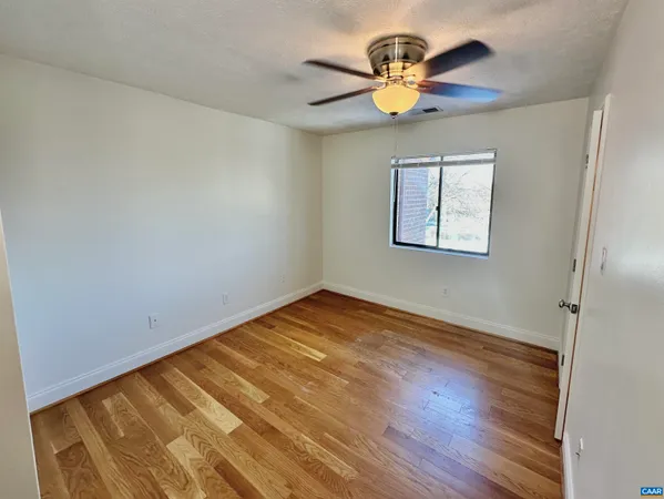an empty room with wooden floor and a window