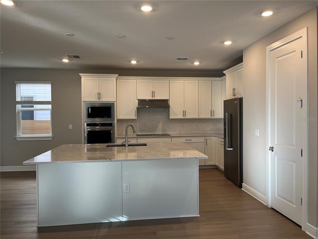 3012 Polaris Drive St. Cloud, FL 34771 - Photo 6 of 21 a large kitchen with stainless steel appliances a large counter top and a refrigerator