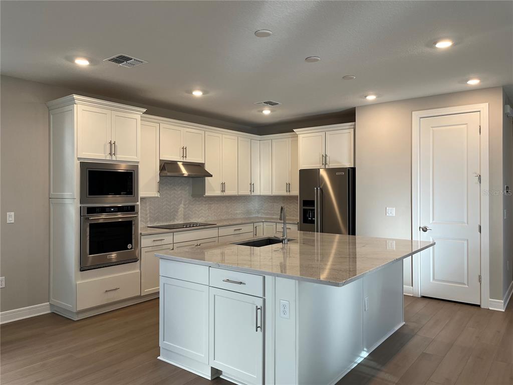 3012 Polaris Drive St. Cloud, FL 34771 - Photo 8 of 21 a large kitchen with stainless steel appliances a large counter top and wooden floors
