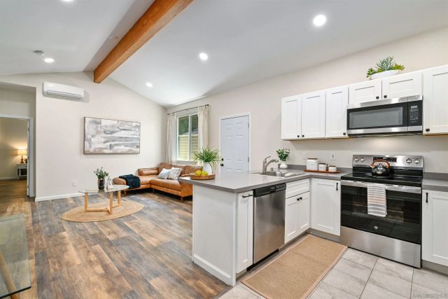 a kitchen with stainless steel appliances a stove a sink a microwave a dining table and chairs