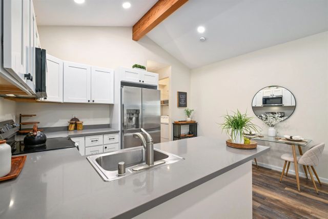 a kitchen with a sink a stove and chairs with wooden floor