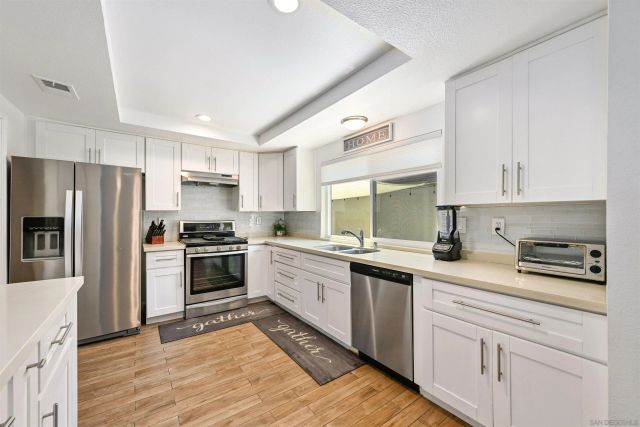 a kitchen with a sink white cabinets and stainless steel appliances