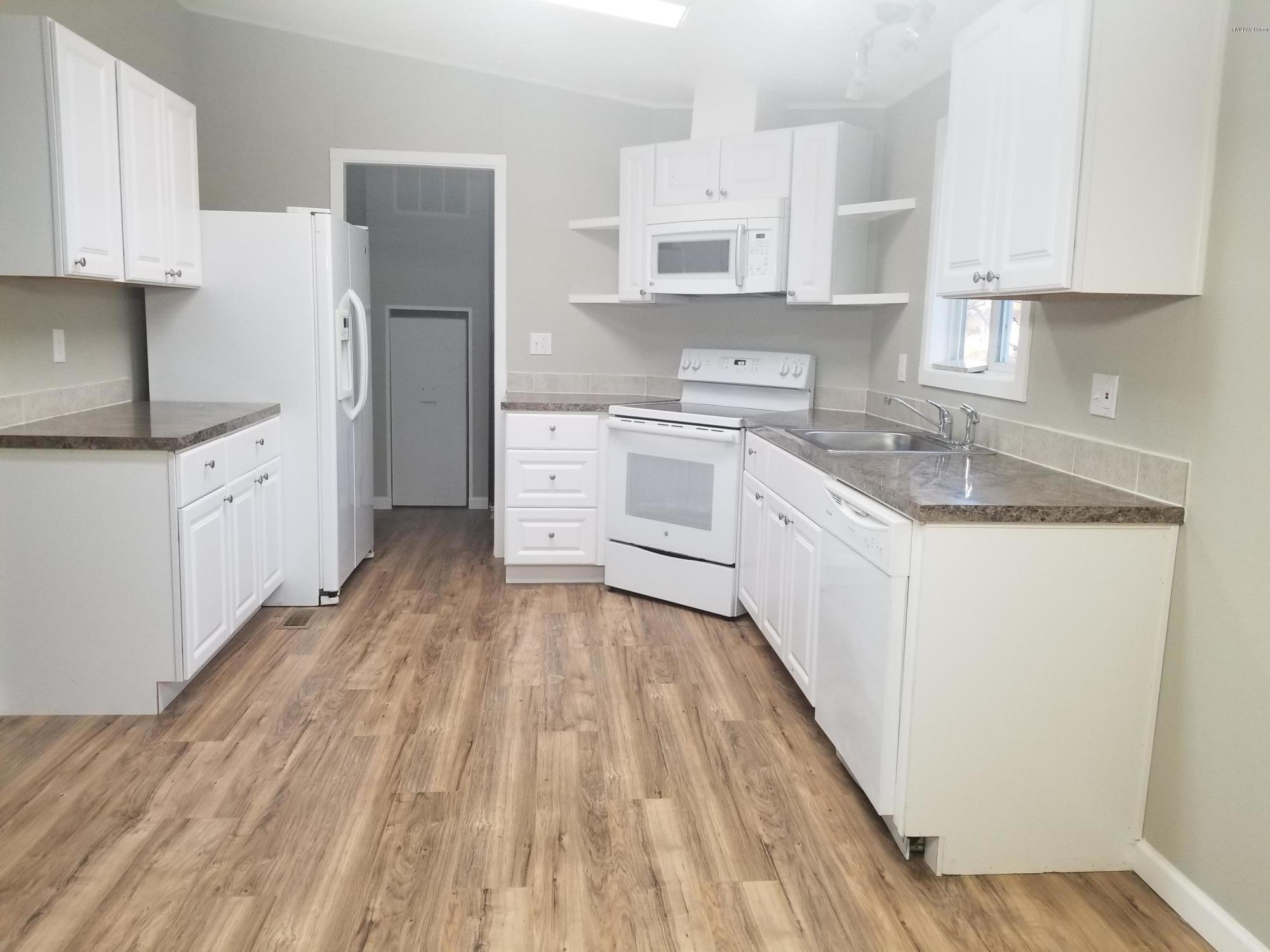 1033 Rader Road Sunnyside, WA 98944 - Photo 4 of 12 a kitchen with granite countertop white cabinets and white appliances