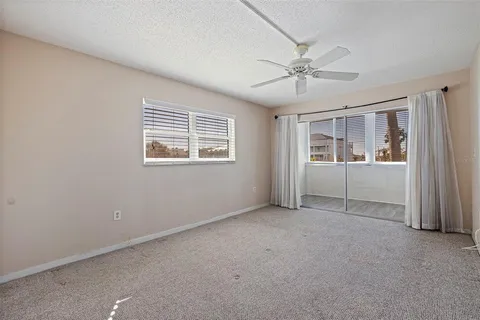 an empty room with chandelier fan and windows