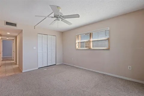 an empty room with chandelier fan and windows