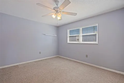 an empty room with a chandelier fan and window