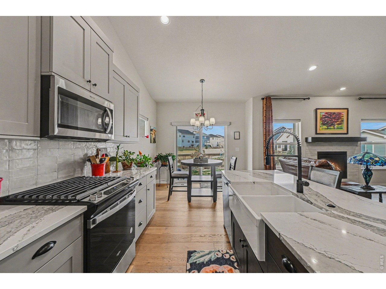 6309 2nd Street Greeley, CO 80634 - Photo 2 of 33 a kitchen with stainless steel appliances granite countertop a stove top oven a sink dishwasher a dining table and chairs with wooden floor