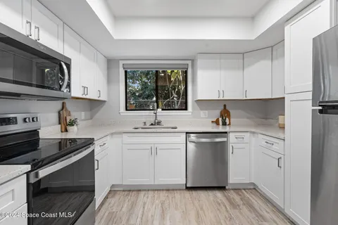 a kitchen with stainless steel appliances granite countertop a stove a sink dishwasher and a microwave oven with wooden cabinets