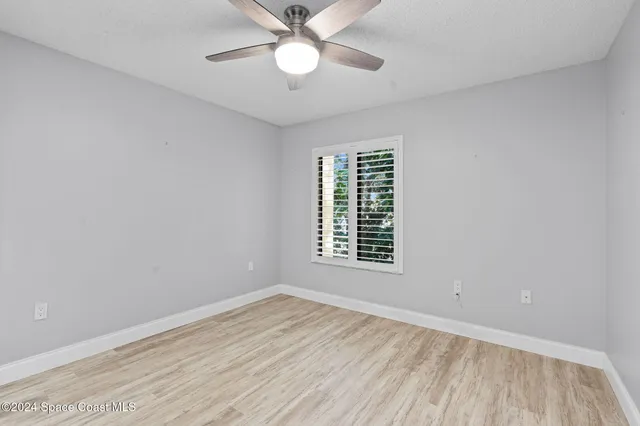an empty room with a window and ceiling fan