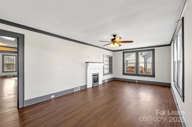 a view of an empty room with a window and wooden floor
