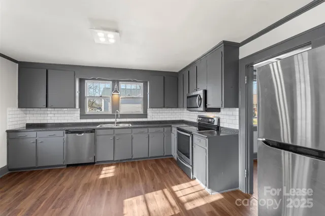 a kitchen with granite countertop stainless steel appliances a sink stove and refrigerator