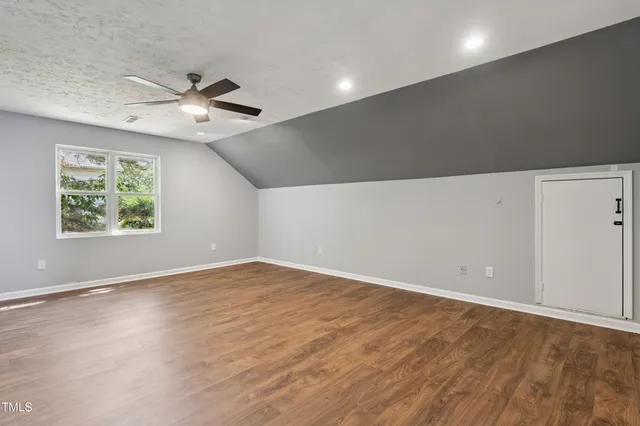 an empty room with wooden floor ceiling fan and windows
