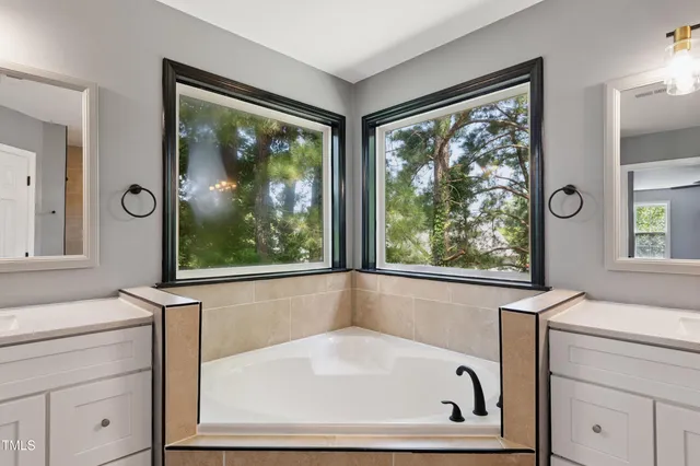 a spacious bathroom with a tub sink shower and mirror