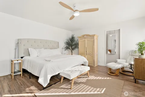 a spacious bedroom with a bed a rug and wooden floor