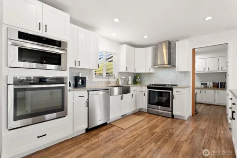 a kitchen with stainless steel appliances a stove a microwave oven cabinets and a wooden floor