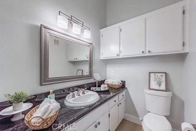 a bathroom with a granite countertop toilet sink and mirror