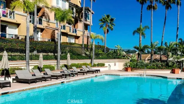 a view of swimming pool with lawn chairs and a large tree