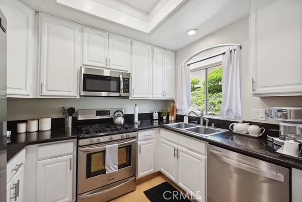 a kitchen with stainless steel appliances granite countertop a sink a stove a microwave and cabinets