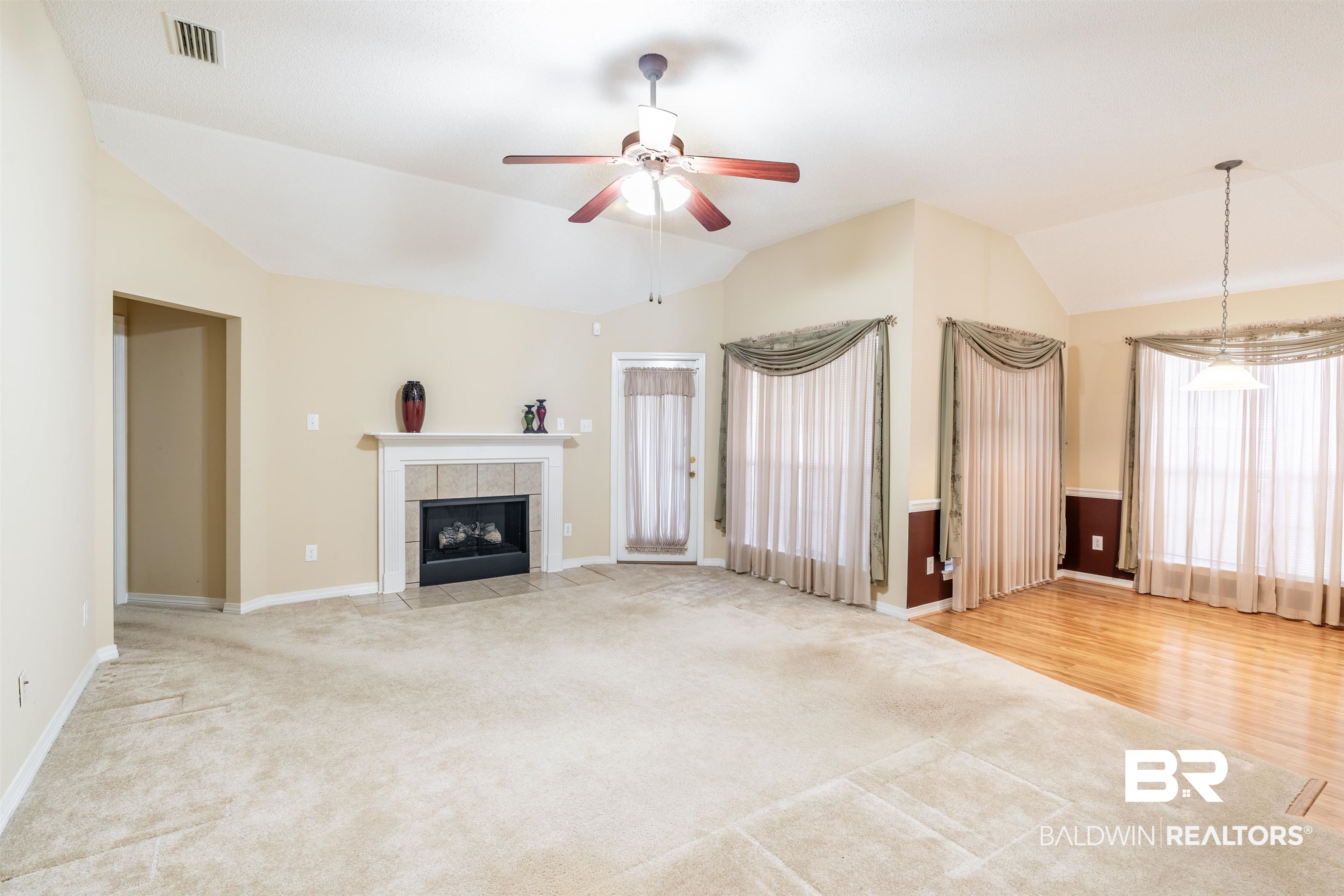 1784 Harrington Way Mobile, AL 36695 - Photo 2 of 18 Unfurnished living room with ceiling fan with notable chandelier, a fireplace, vaulted ceiling, and carpet