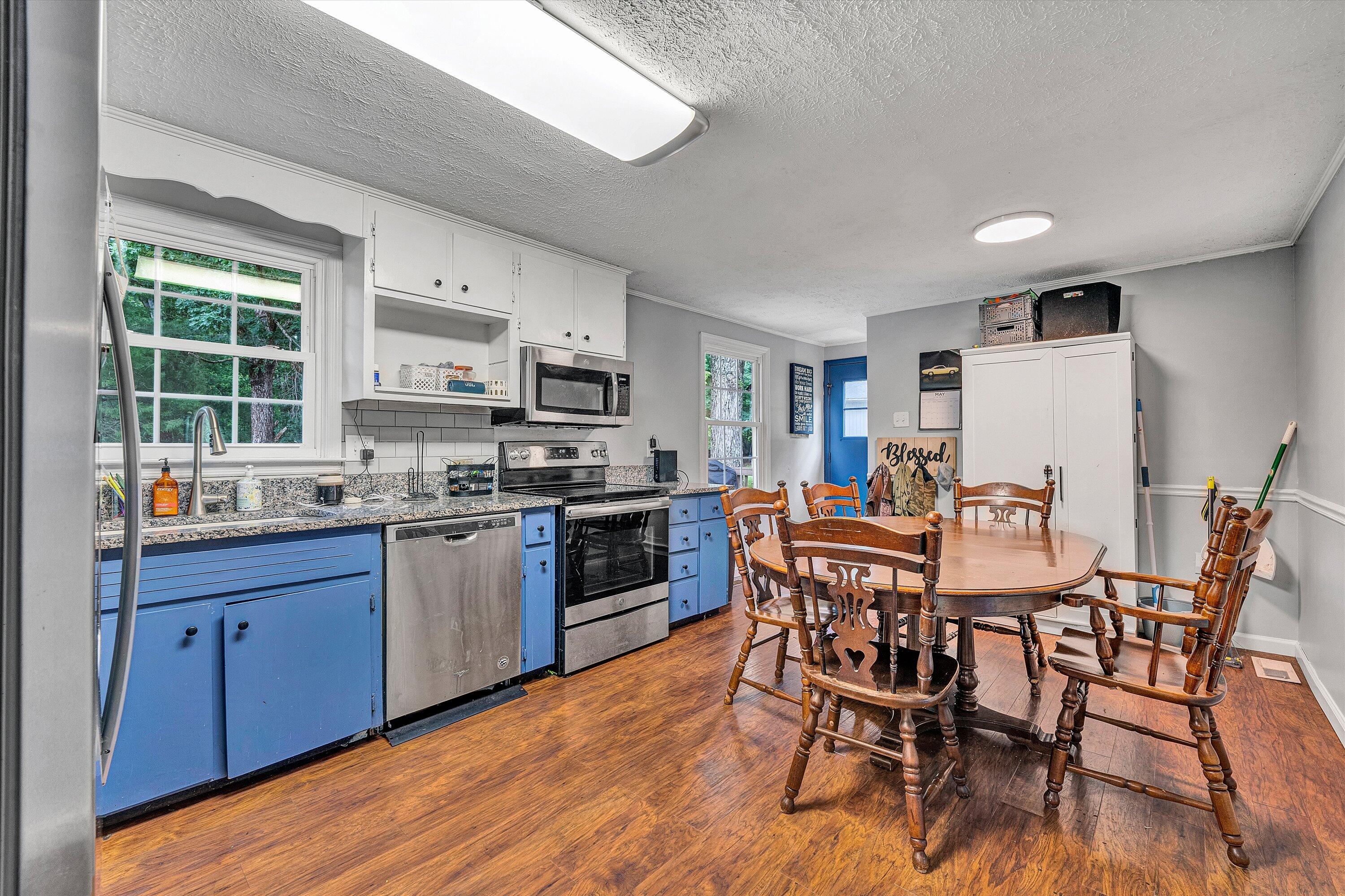 2095 Webster Road Glade Hill, VA 24092 - Photo 5 of 20 a kitchen with stainless steel appliances granite countertop a table chairs microwave and sink