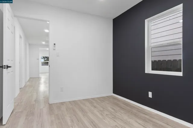 a view of a hallway with wooden floor and a bathroom