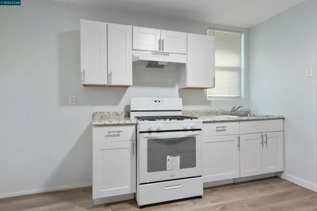 a kitchen with granite countertop white cabinets and white appliances