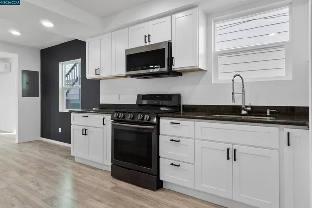 a kitchen with granite countertop white cabinets and stainless steel appliances