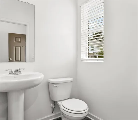 a bathroom with a toilet a sink a mirror and a window
