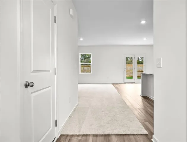 a view of hallway with wooden floor and a bathroom