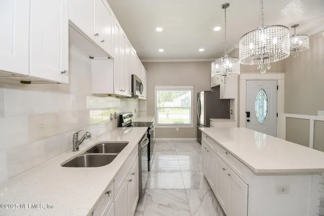 a kitchen with granite countertop a sink a counter top space appliances and cabinets