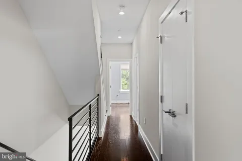 a view of a hallway with wooden floor and a bathroom