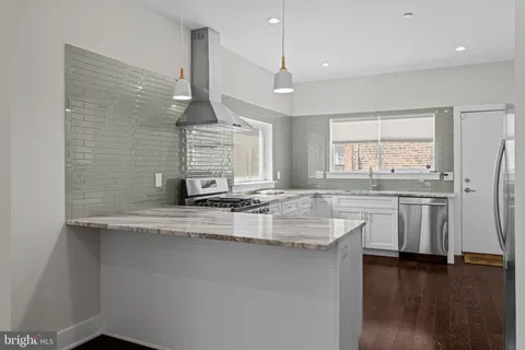 a kitchen with stainless steel appliances granite countertop a sink a counter space and a window