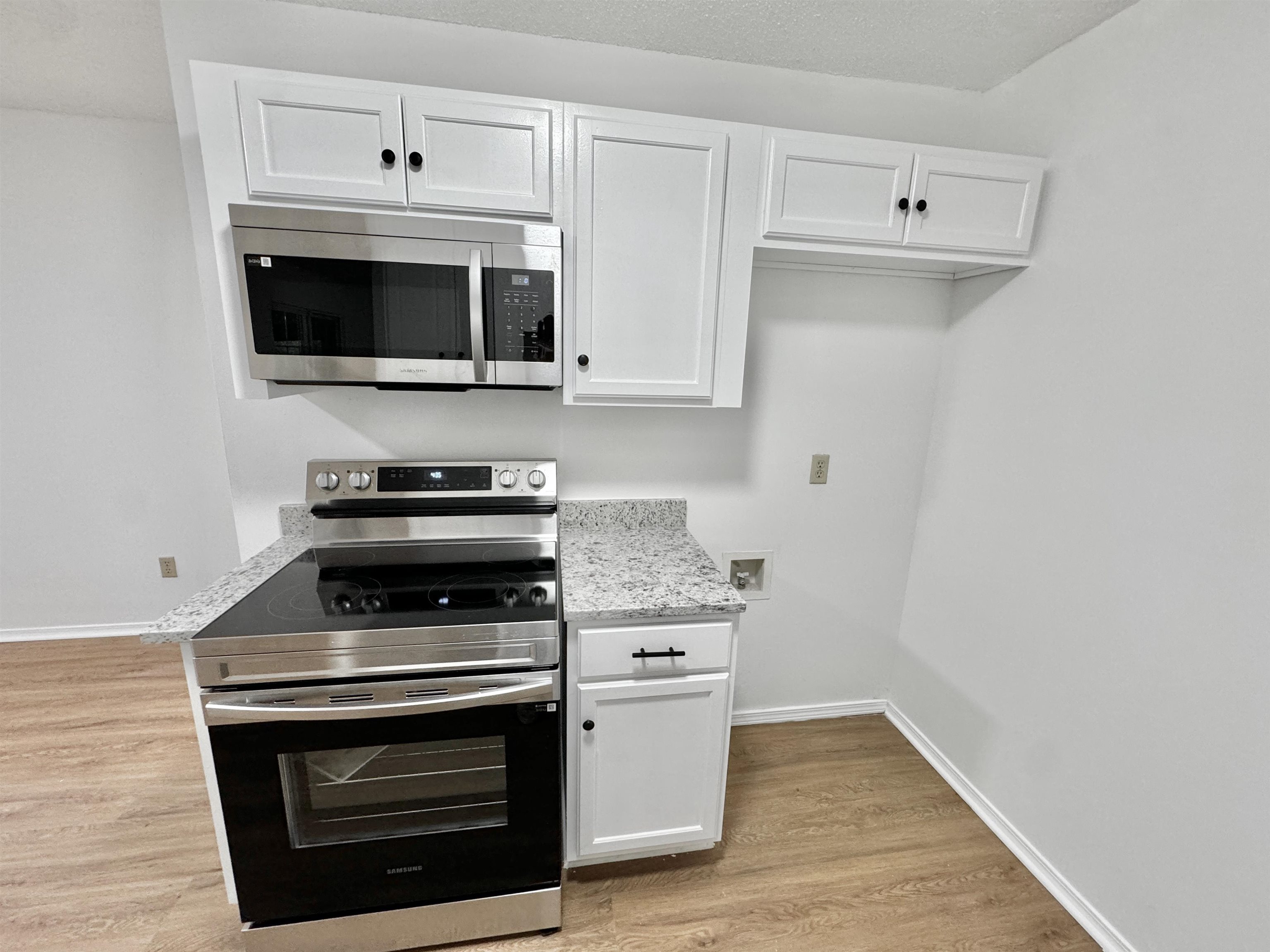 520 Stone Road Pinson, TN 38366 - Photo 5 of 30 Kitchen with light wood finished floors, light stone countertops, white cabinetry, and stainless steel appliances