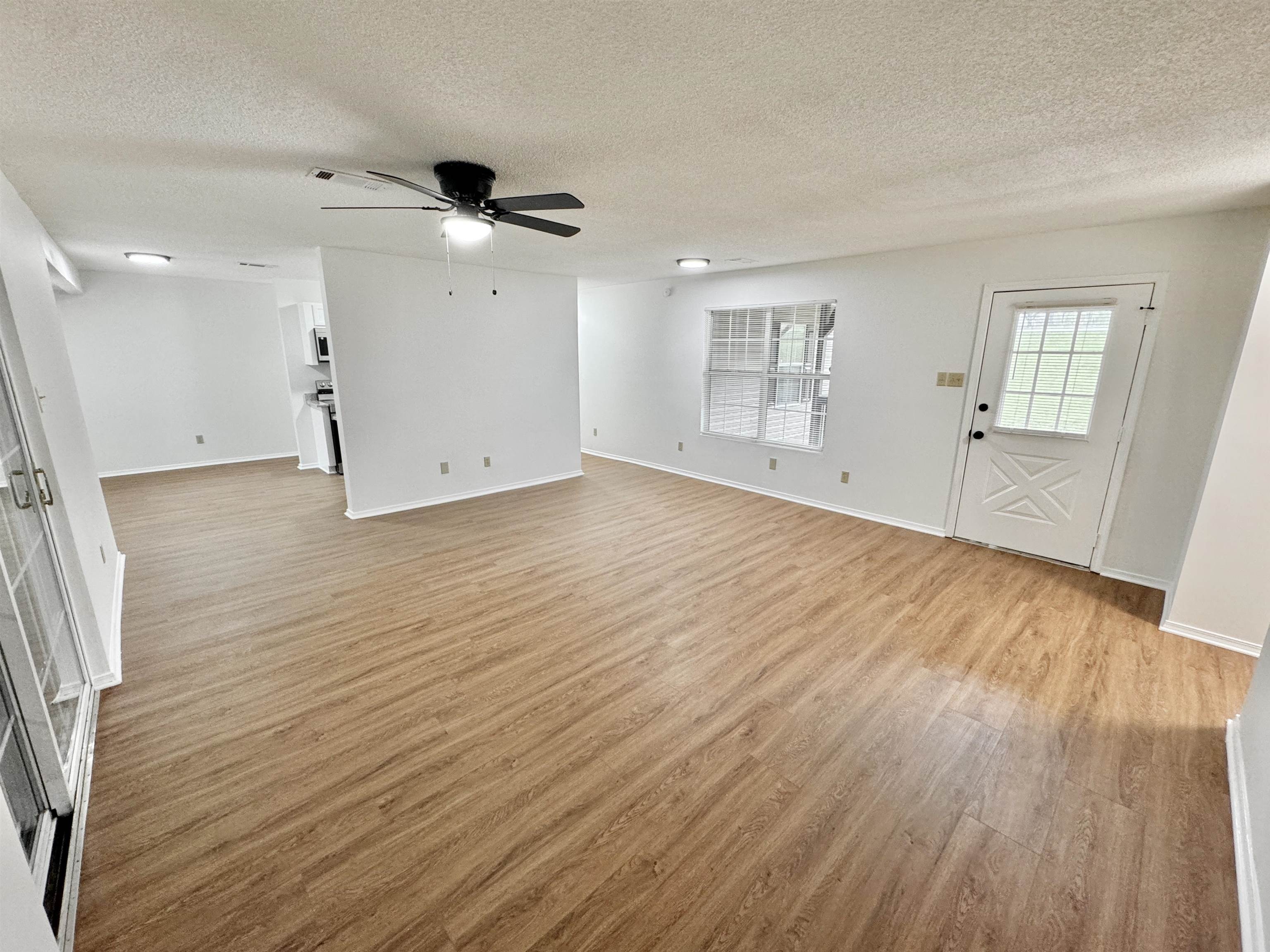 520 Stone Road Pinson, TN 38366 - Photo 9 of 30 Unfurnished living room with a textured ceiling, ceiling fan, light wood-type flooring, and baseboards