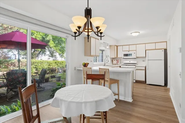 a kitchen with kitchen island a stove a refrigerator a dining table and chairs with wooden floor