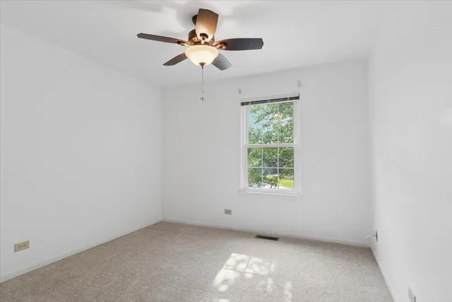 an empty room with a window and a fan