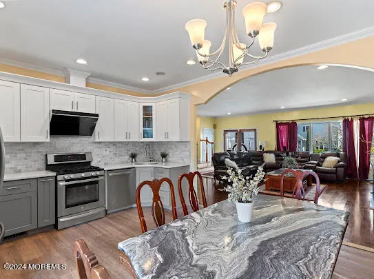 a kitchen with stainless steel appliances granite countertop a sink dishwasher a dining table and chairs with wooden floor